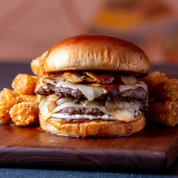 A double patty burger with melted cheese, mushrooms, and onions, served with tater tots.