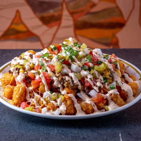 Loaded tater tots from Dusty's Hideaway, topped with ground beef, cheese, tomatoes, onions, and sauce.